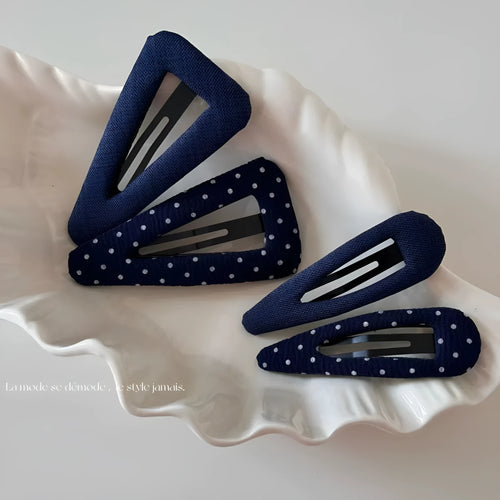 Dark denim barrette with white polka dots in a triangle shape next to a water drop shaped barrette.