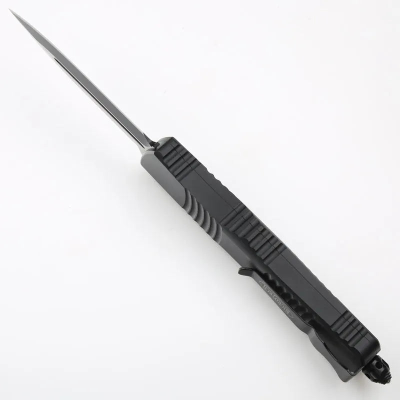 Black folding knife with D2 steel blade and aviation aluminium handle open on a dark surface