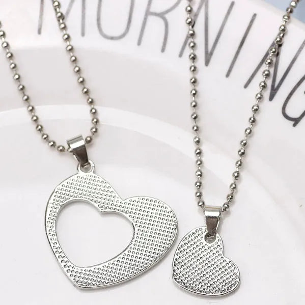 Two silver alloy heart-shaped puzzle necklaces on cross chains, matching set