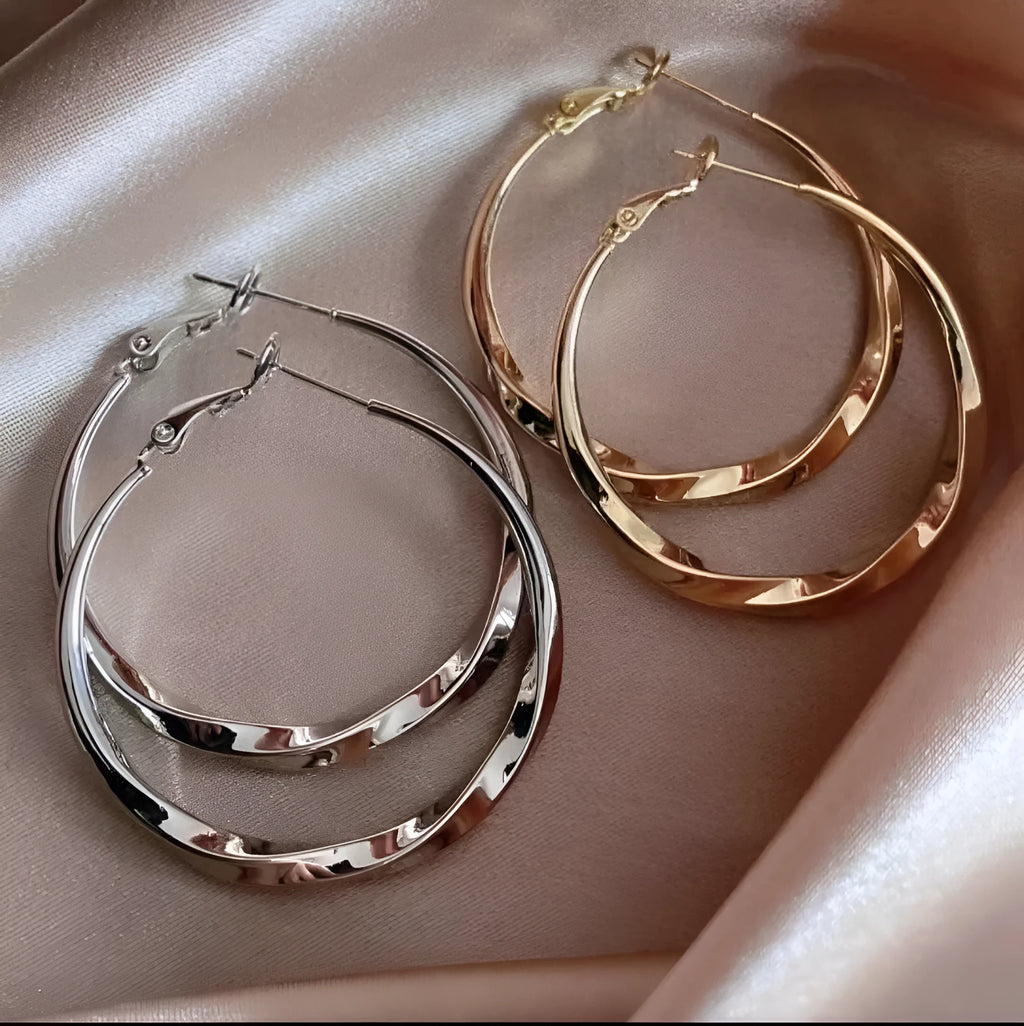 Twisted eyelet simple metal earrings in 3499 Gold and 3499 Silver on neutral background