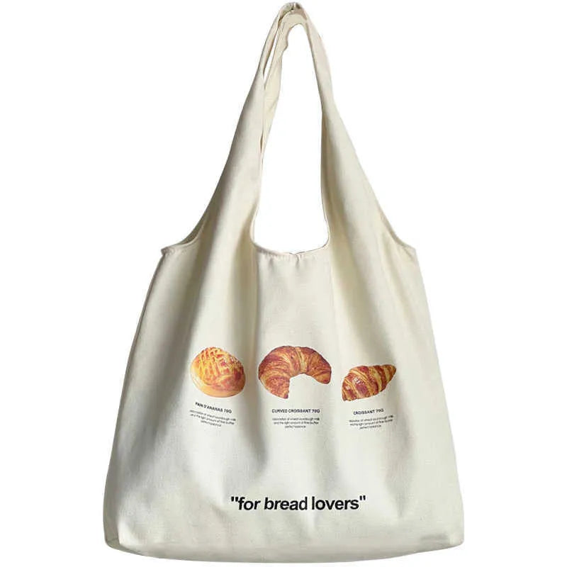 Beige canvas tote bag with bread print design showing adjustable shoulder strap and structured base
