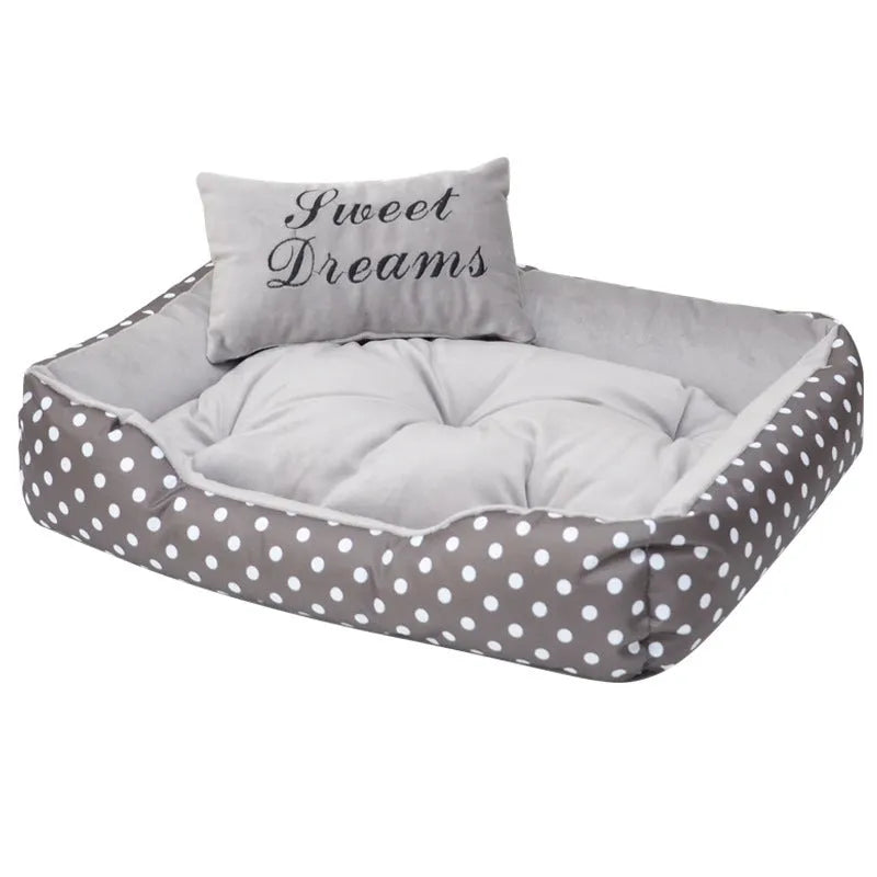 Polka dot square dog bed with matching embroidered pillow in grey, shown in a home setting.