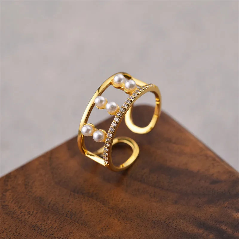 Gold electroplated geometric women's ring with an open adjustable design on a plain background