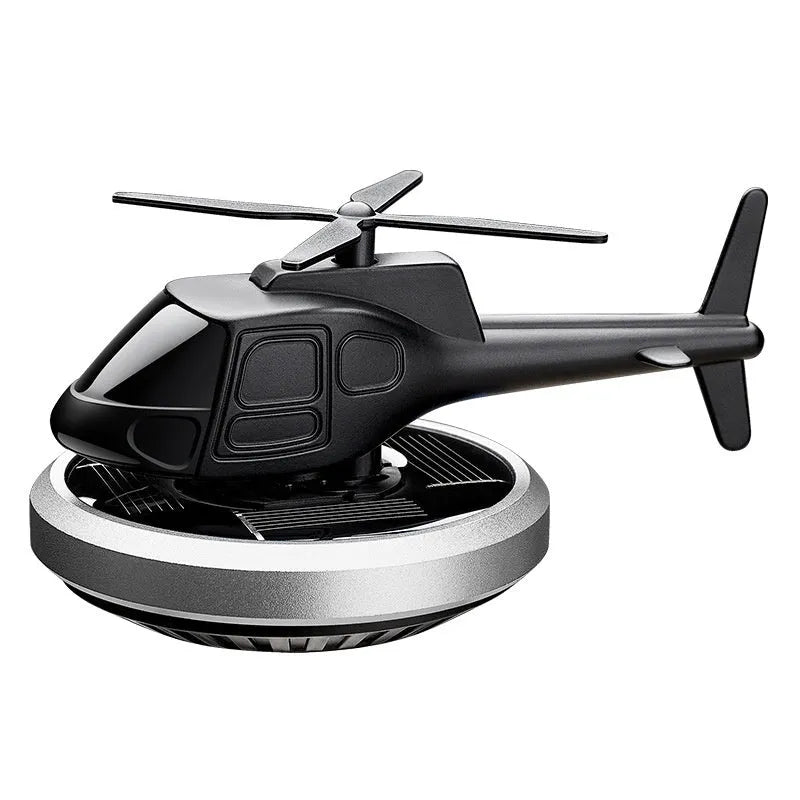 Silver solar-powered rotating metal car air freshener ornament on a dashboard.