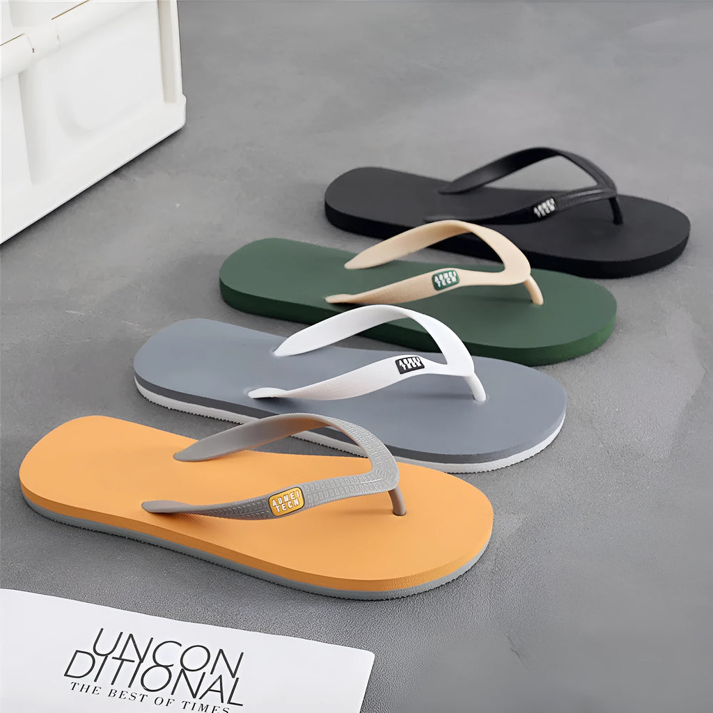 Men's black flip-flops with a textured rubber sole and EVA foam upper on a sandy beach.