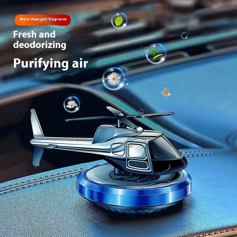 Silver solar-powered rotating metal car air freshener ornament on a dashboard.