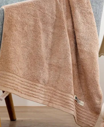 Set of three cotton towels in beige and brown colours, showing small, medium, and large sizes.