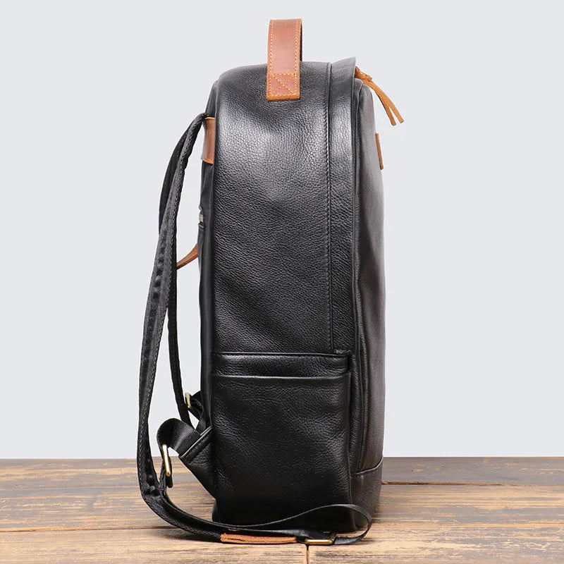 Black genuine leather expandable backpack with top grain cowhide, curved shoulder straps, and patchwork detail