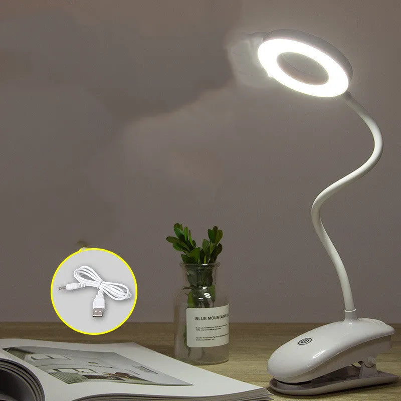 Modern clip-on rechargeable desk lamp with a white plastic shade and touch controls on its base.