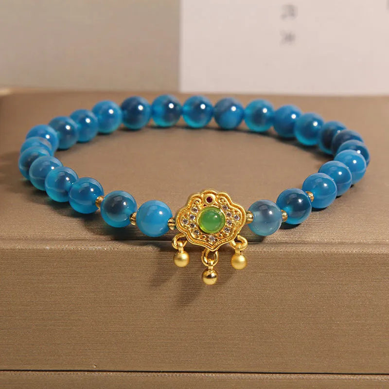 Blue sugar heart agate safety lock pendant on a women's crystal bracelet with rhinestone details.