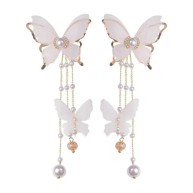 A pair of white butterfly-shaped earrings with lace, pearl, rhinestone and tassel details on a copper alloy base.