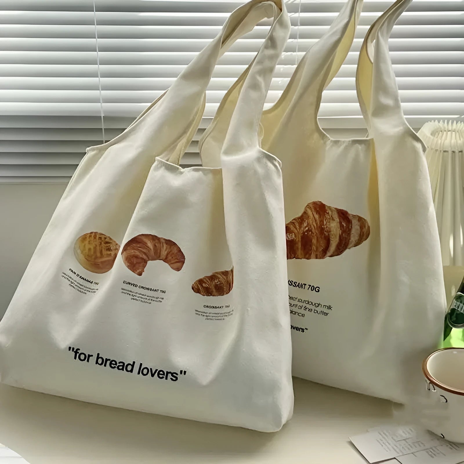 Beige canvas tote bag with bread print design showing adjustable shoulder strap and structured base