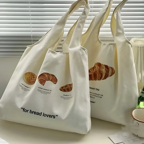 Beige canvas tote bag with bread print design showing adjustable shoulder strap and structured base