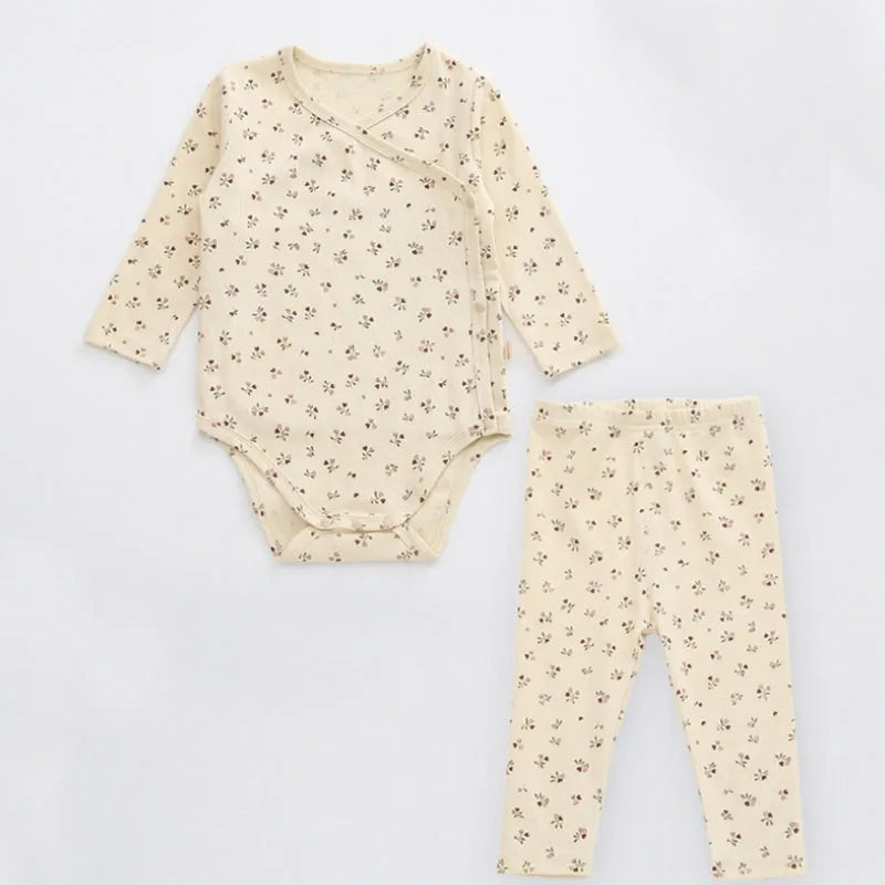 Newborn baby cotton romper two-piece suit in neutral style with top, pants, and matching hat on a white background
