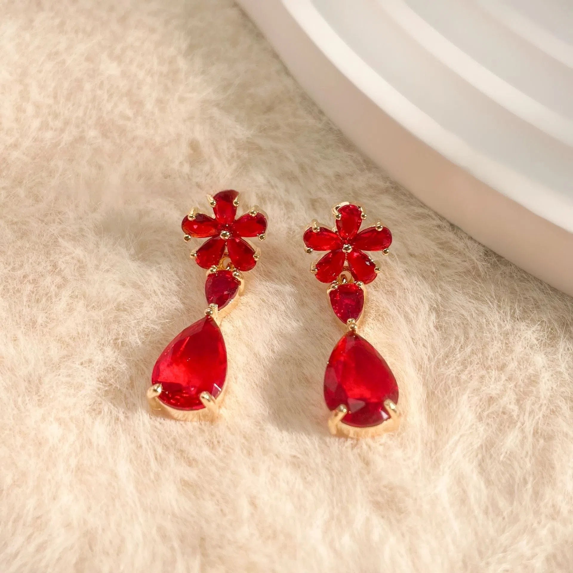 Gold flower tassel stud earrings with copper electroplated finish on light background