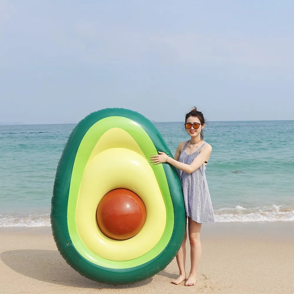 Large green inflatable avocado pool float on blue water.