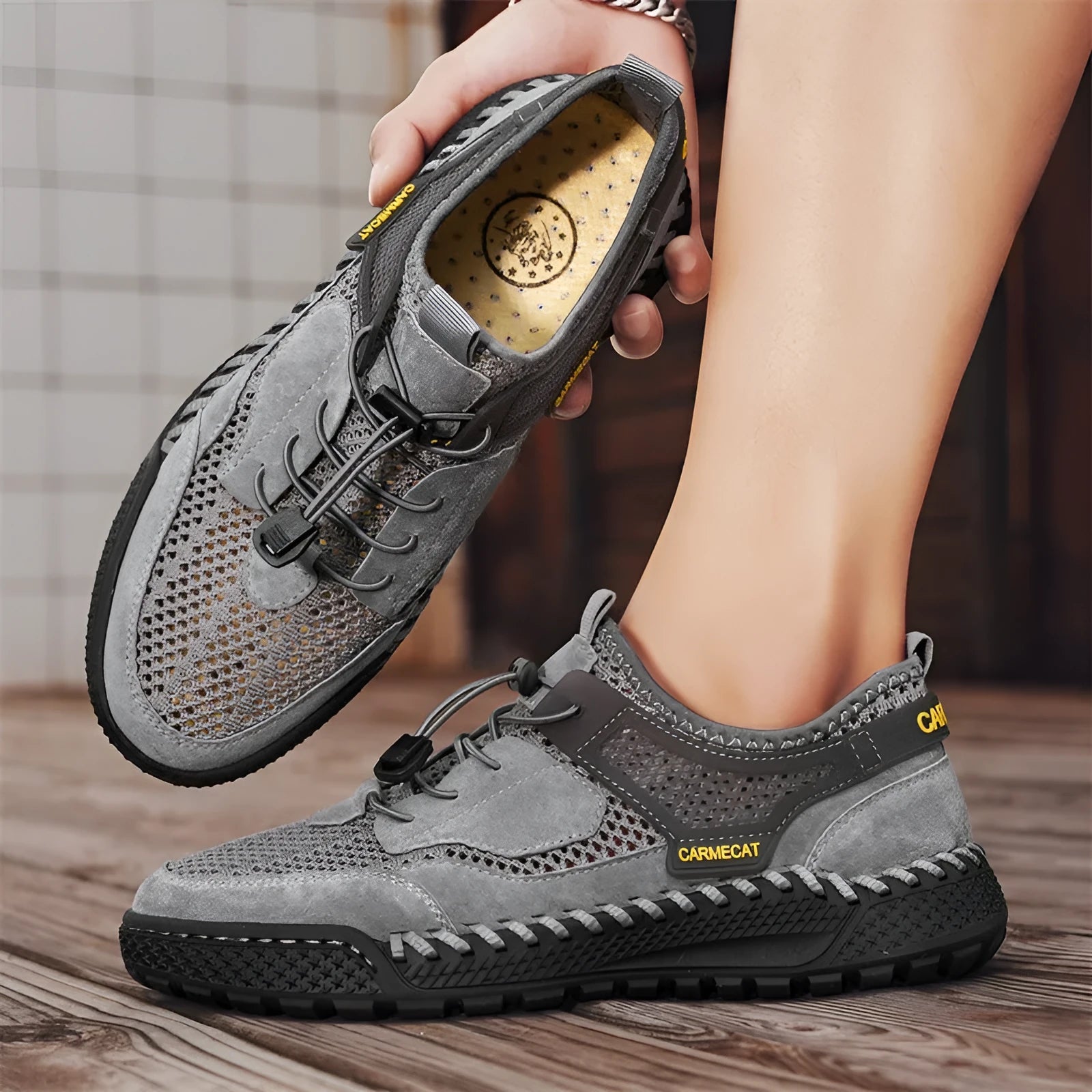 Men's brown suede low-top casual tennis shoes with a visible elastic band and hand-stitched rubber sole.