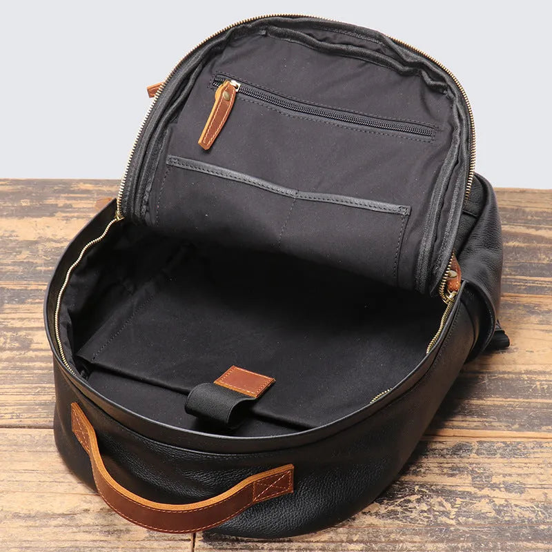 Black genuine leather expandable backpack with top grain cowhide, curved shoulder straps, and patchwork detail