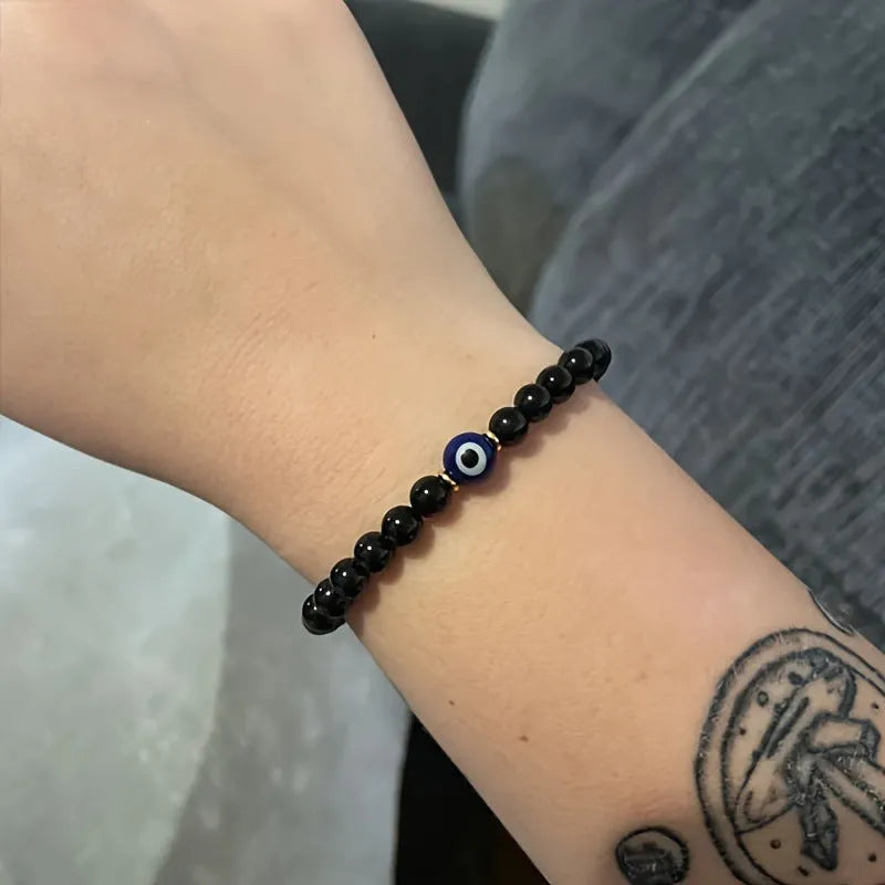 Men's black 8mm devil's eye obsidian beaded bracelet with geometric pattern on table