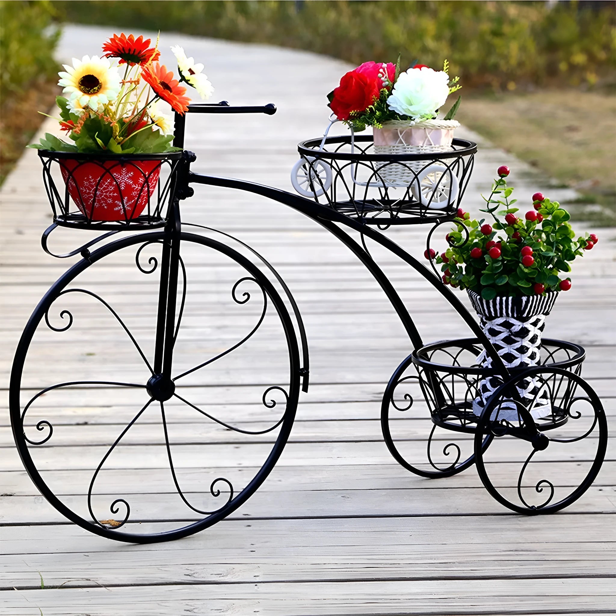 Black wrought iron tricycle plant stand with three round baskets holding small potted plants on a patio
