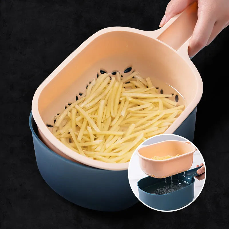 Dark blue vegetable cutter with four stainless steel blades, a drain basket, and a hand guard on a kitchen counter.