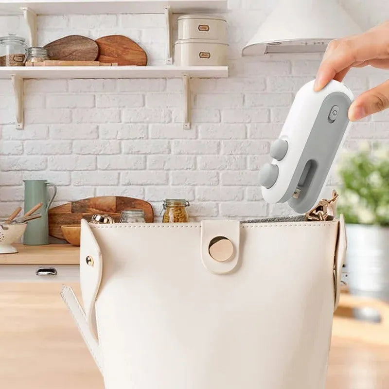Blue and white handheld USB rechargeable heat sealer with magnetic back on a metal surface.