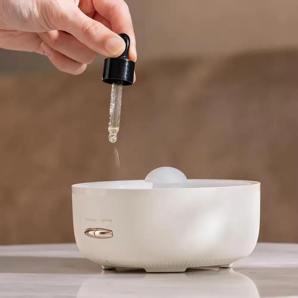 Round beige resin aroma diffuser with one fog outlet and colourful light on a desktop