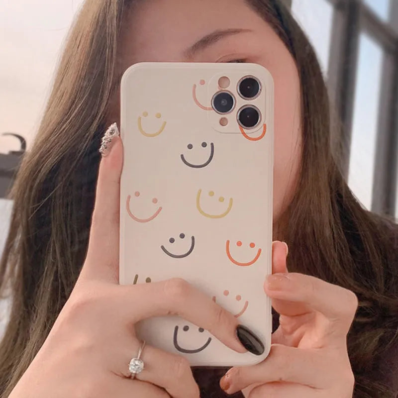 Simple TPU silicone iPhone case with painted smiley face and graffiti design on a table