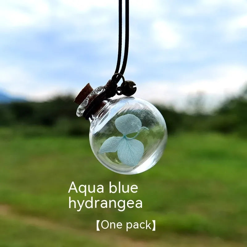 Glass car perfume pendant with preserved flower decoration hanging in car interior