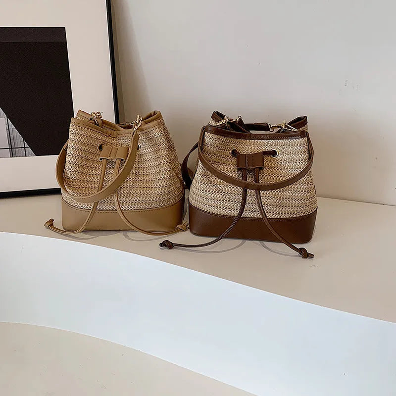 Brown woven straw women's crossbody bucket bag with a long adjustable strap.