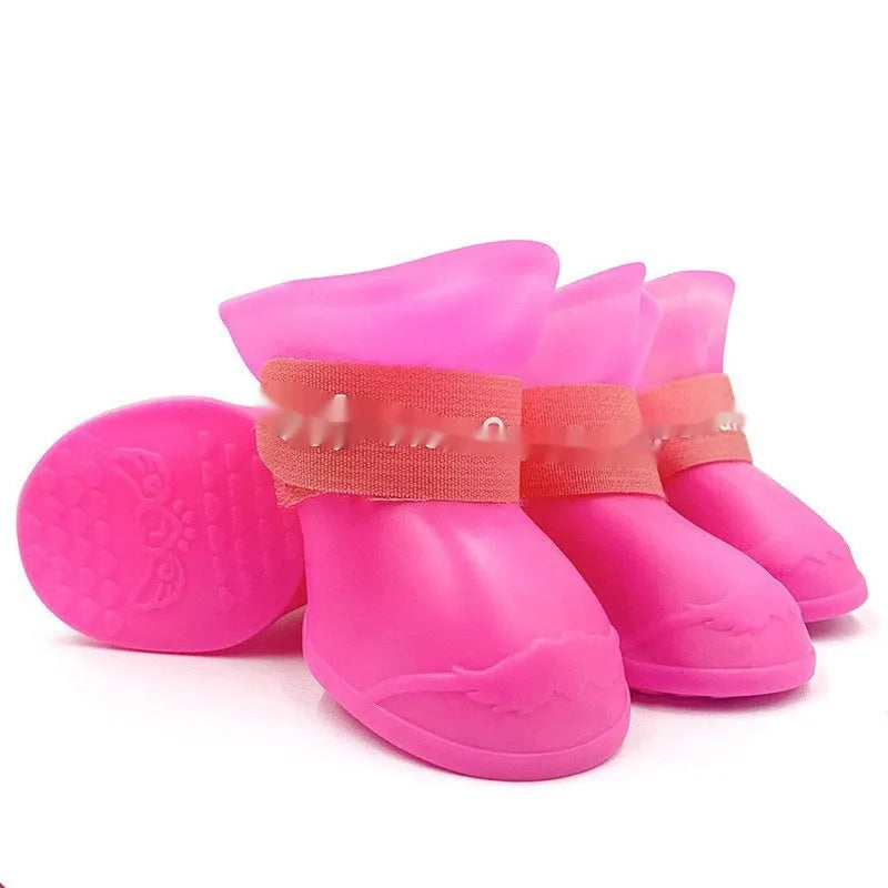 Set of four soft-soled rubber pet rain shoes in assorted colours on a grey background.