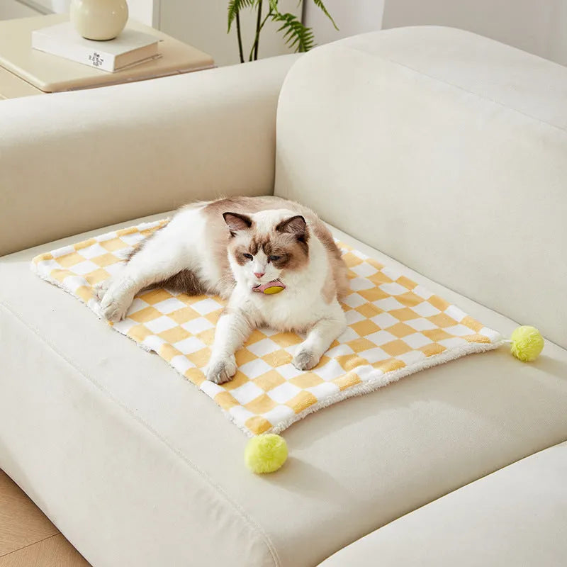 Soft plaid pattern pet blanket with fur ball decoration on a sofa