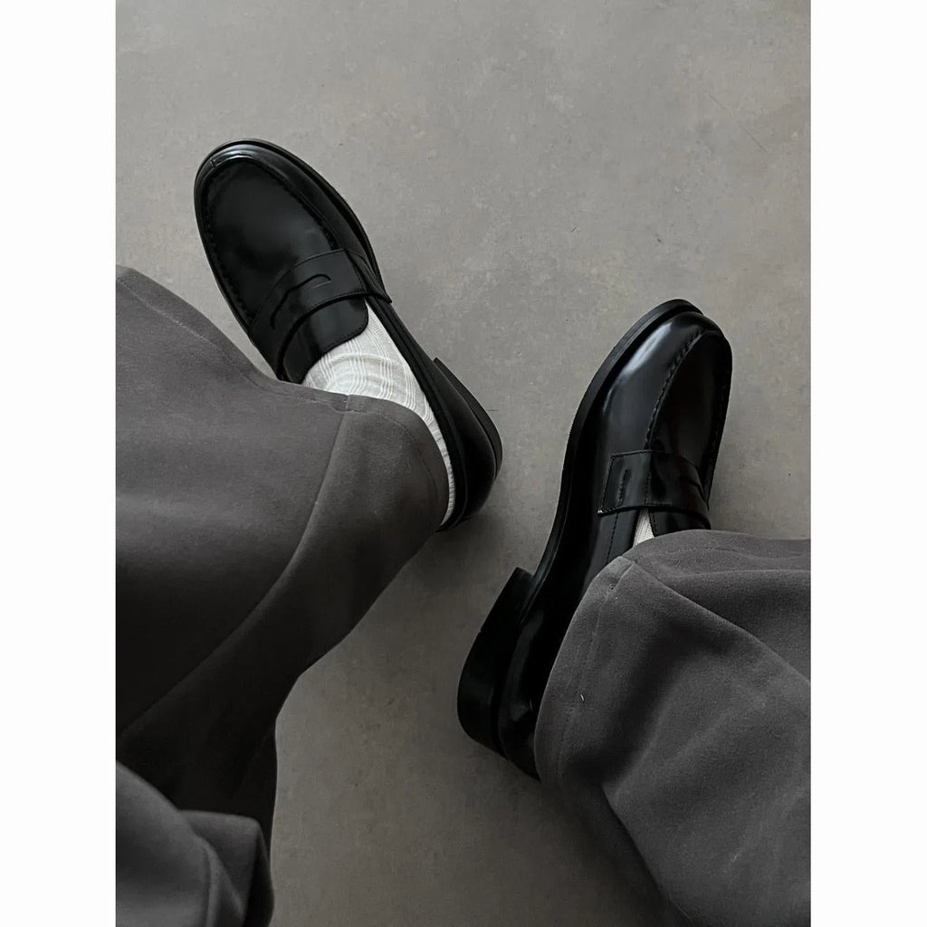 Men's black leather loafers with stitched seams, square heel, and vulcanised rubber sole on display
