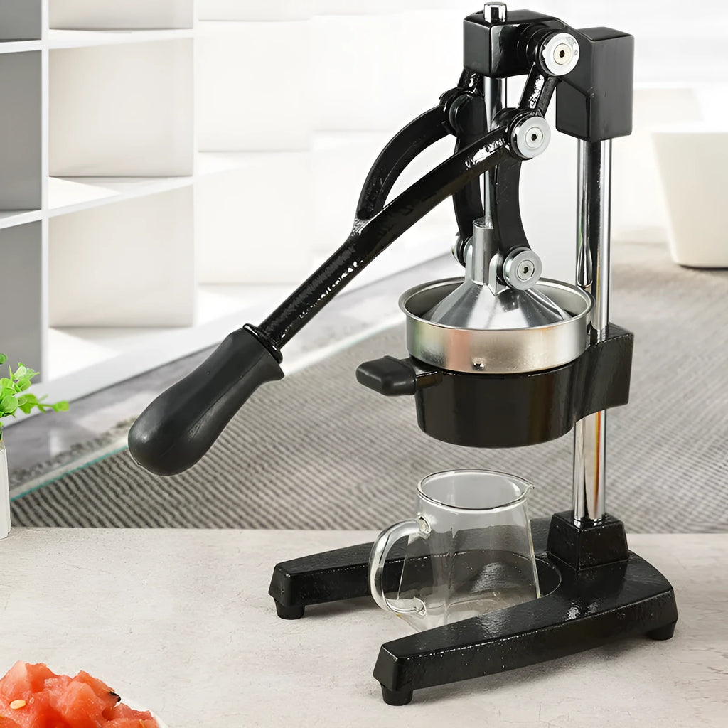 Black manual cast iron citrus juicer with stainless steel funnel on a kitchen counter.