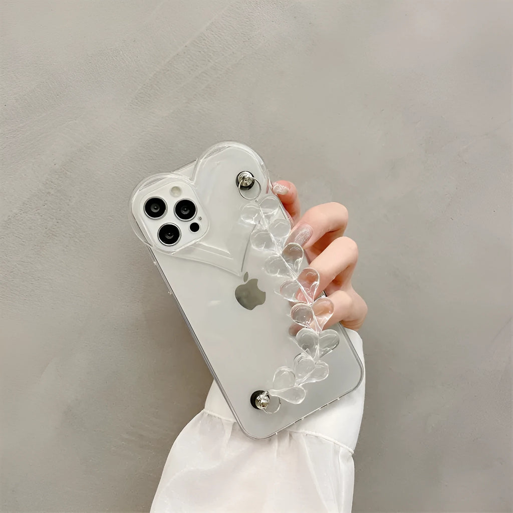 Clear iPhone case with transparent love heart bracelet charm attached, showing soft TPU material.