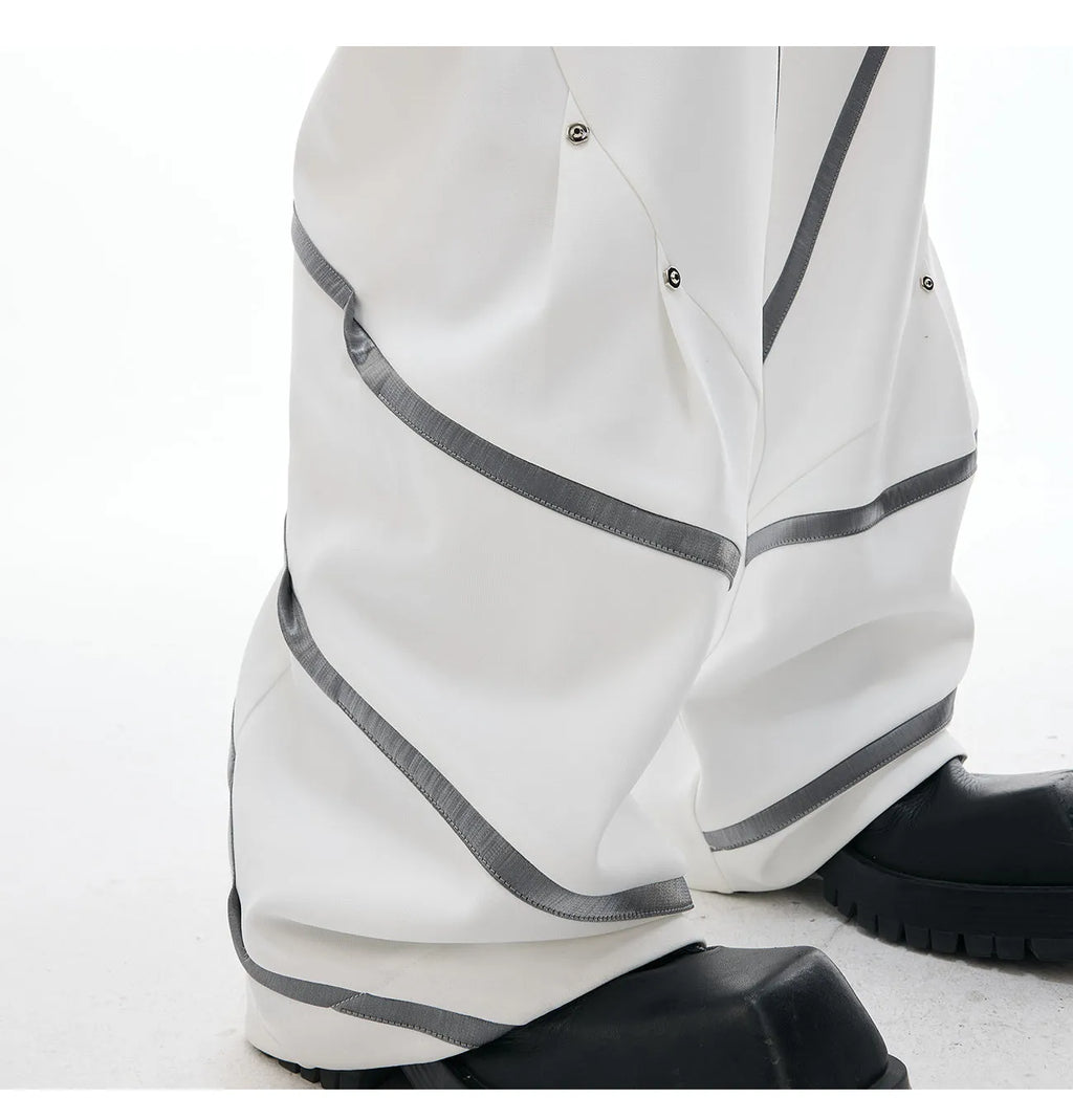 Men's polyester trousers with pleats and metal rivet detailing, shown in black and white colour options.