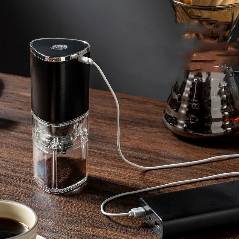 White portable electric coffee grinder with ceramic burr and USB charging cable on a kitchen counter.