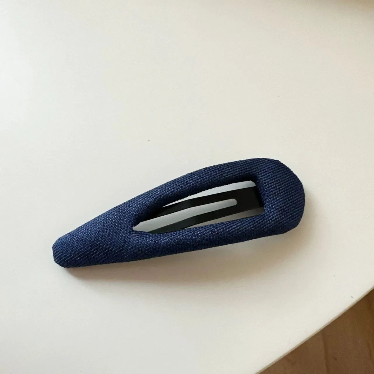 Dark denim barrette with white polka dots in a triangle shape next to a water drop shaped barrette.