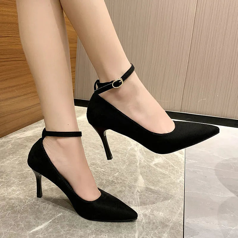 Women's black and creamy white stiletto heel pumps with a buckle fastening.