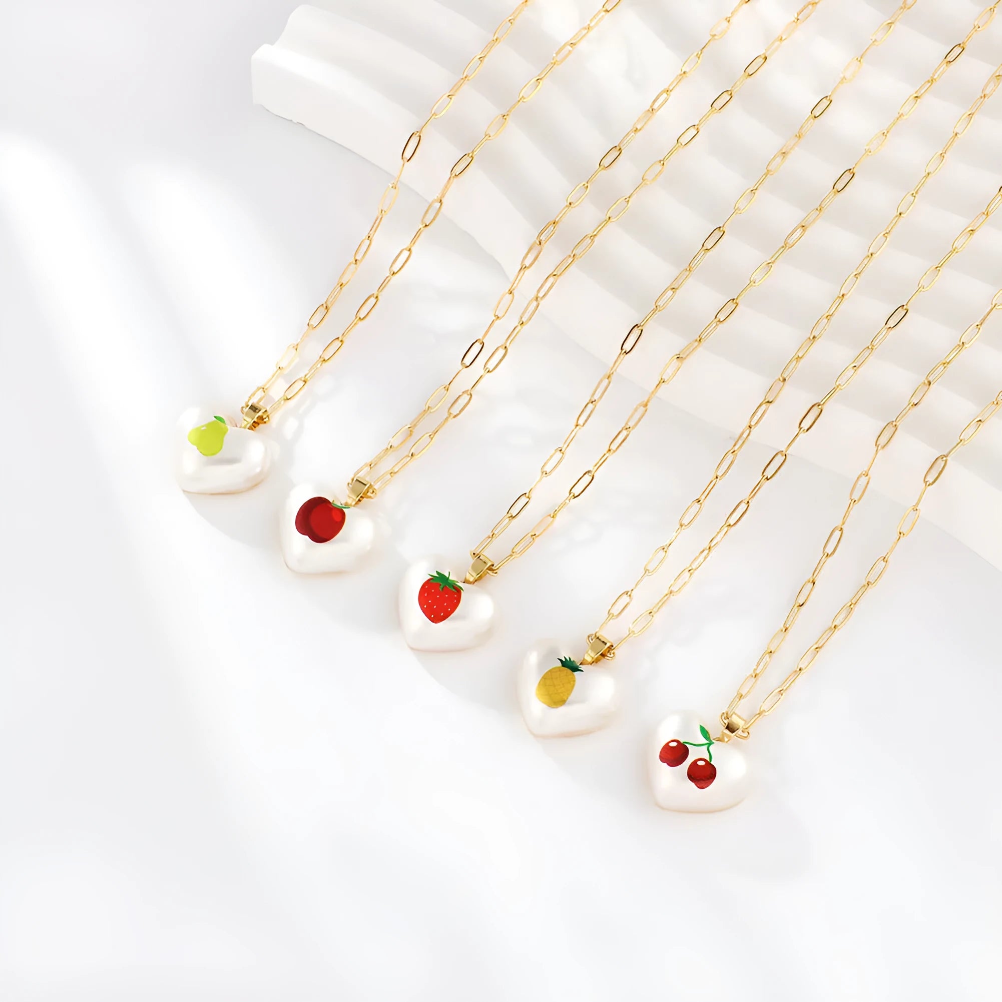 Heart-shaped necklace with geometric chain and a detailed fruit pendant charm, adjustable from 21cm to 50cm.