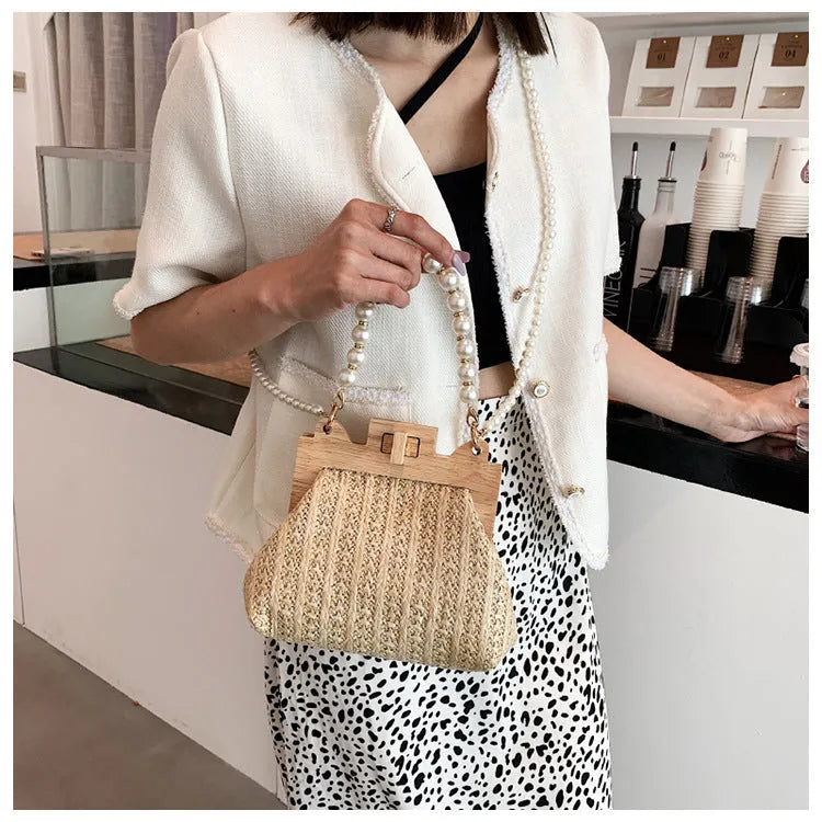 Women's straw woven shoulder bag with pearl chain strap showing interior organisation pockets