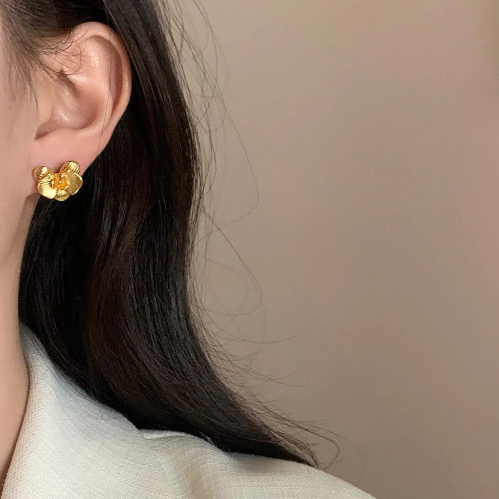 A pair of retro-style flower earrings with petal design, shown in gold electroplated finish.