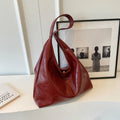 Soft black PU leather shoulder bag with large compartment and adjustable strap on a plain background.