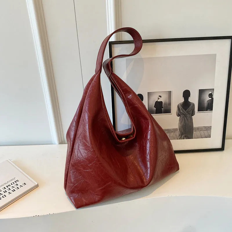 Soft black PU leather shoulder bag with large compartment and adjustable strap on a plain background.