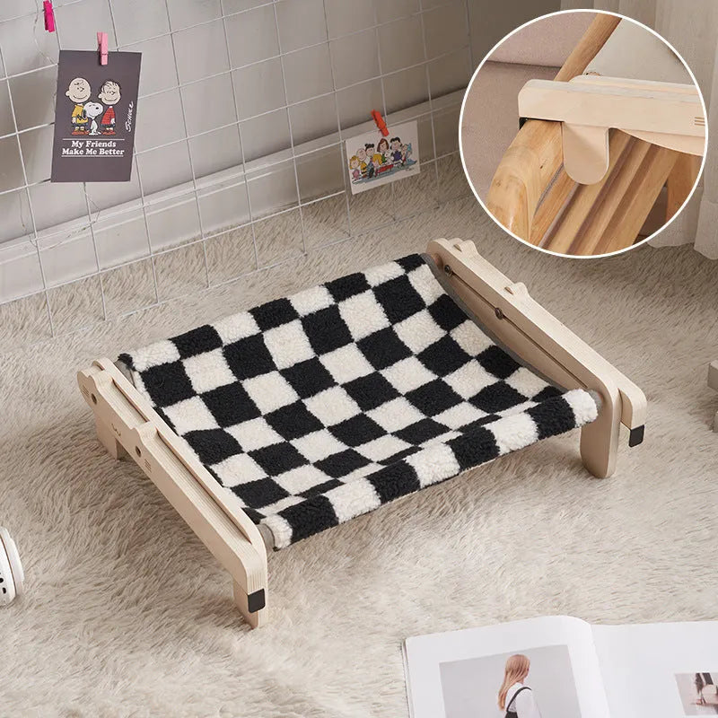 Solid wood cat bed with a removable plaid cushion on a wooden frame.