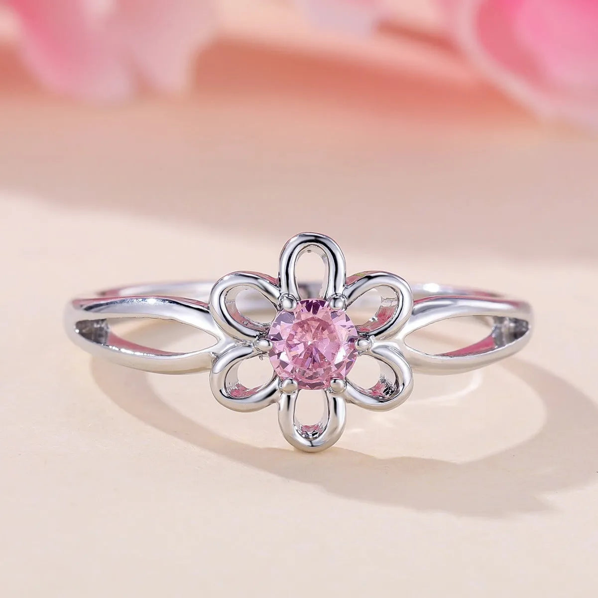 Women's hollowed flower fashion ring in electroplated platinum pink diamond colour on a white background.