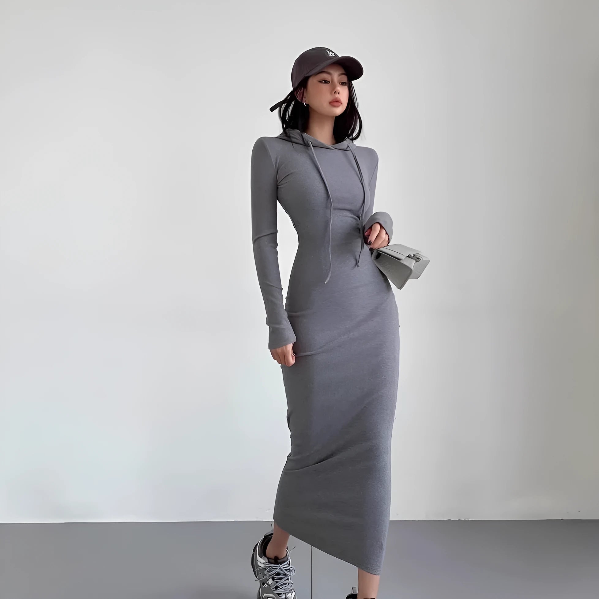 A woman's light grey hooded sheath dress with long sleeves, high waist, and over-the-knee length.