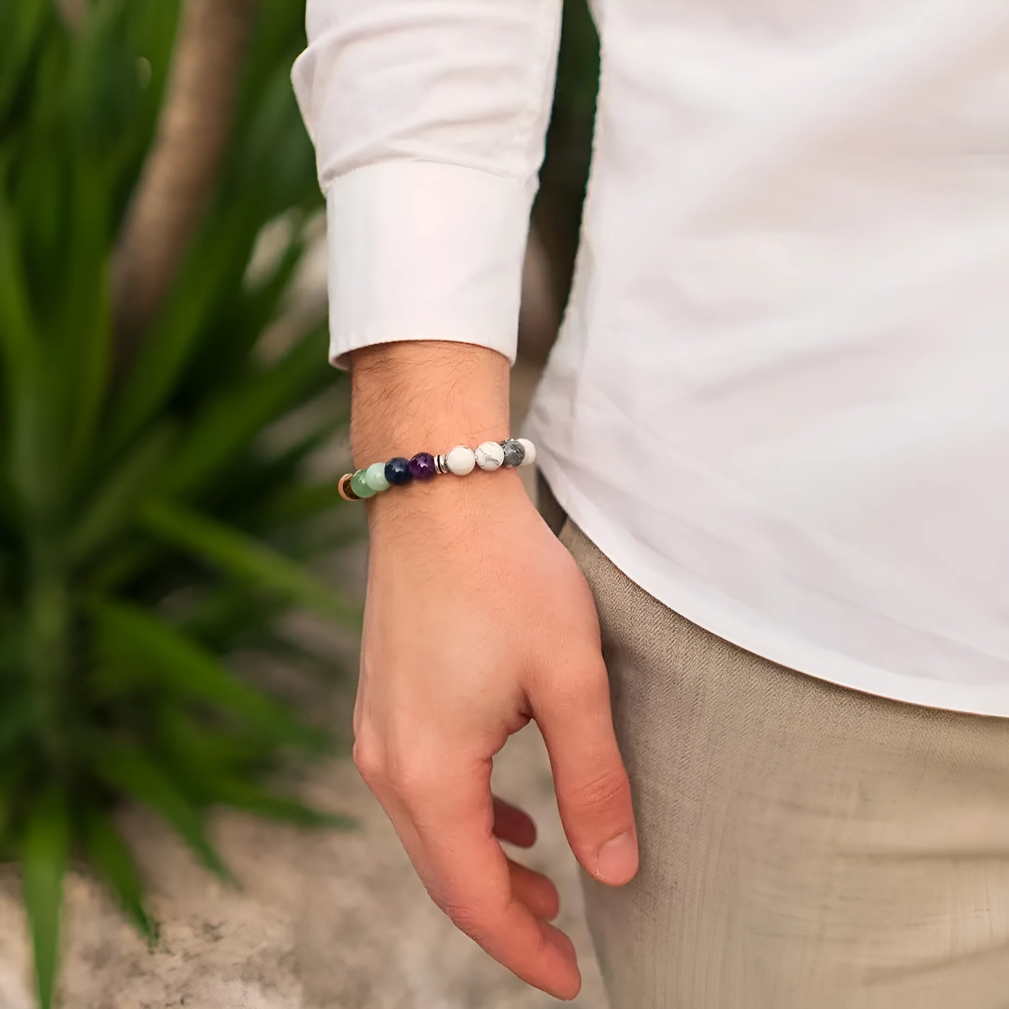 Close-up of a hand-woven flat knot braided bracelet with assorted gemstone beads on a female wrist.