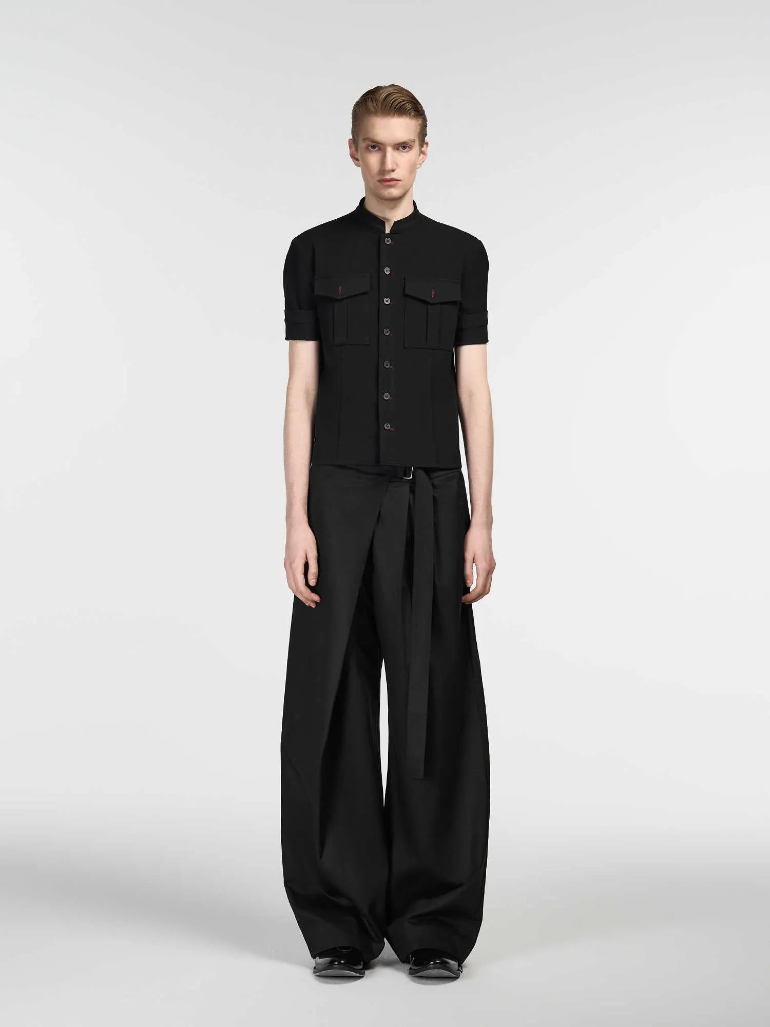 Black single pleated straight-leg trousers with an adjustable waistband on a hanger.