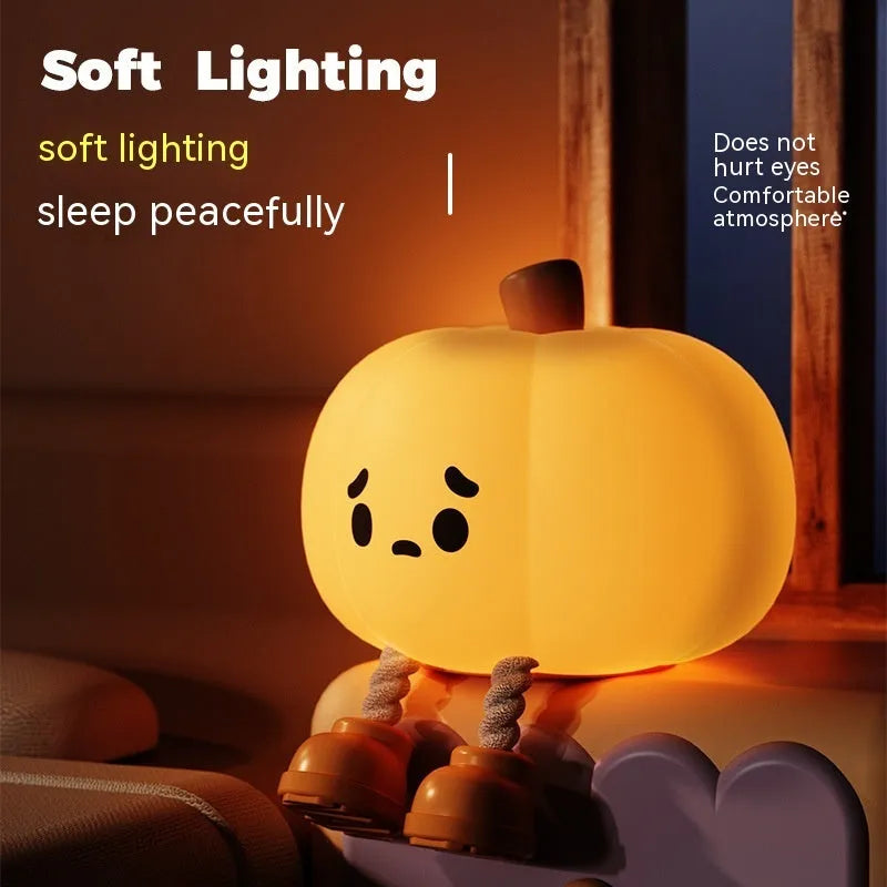 Soft orange pumpkin-shaped silicone night light with a warm glow, showing its compact size on a table.